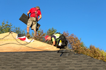 Roofing crew working on a shingle roof